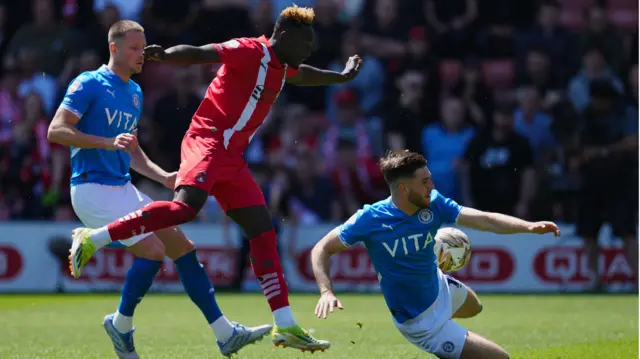 Ethan Pye of Stockport County and Fraser Horsfall of Stockport County block the shot by Dan Agyei of Leyton Orient