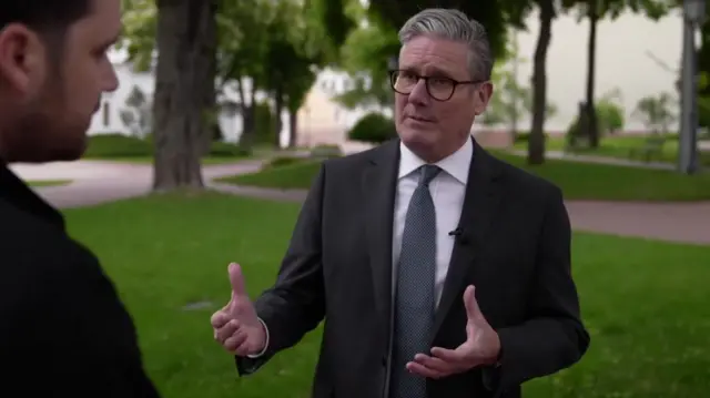 Starmer speaking to Henry Zeffman in Kyiv, wearing glasses and a suit.