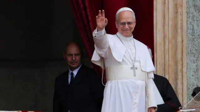 Pope Leo on balcony, waving and smiling.