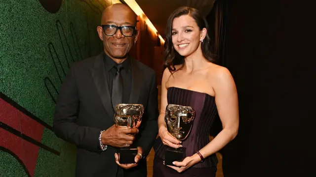 Lennie James and Marisa Abela pose with their awards in a corridor with green glitter walls to one side