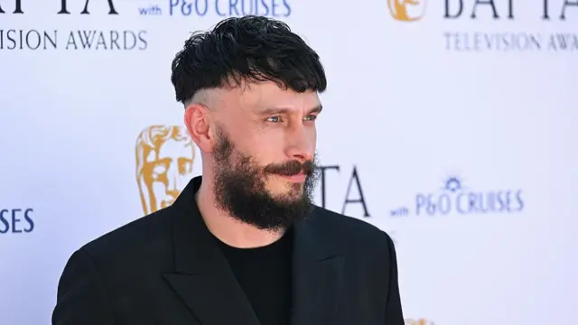 Richard Gadd in black blazer and shirt poses on red carpet