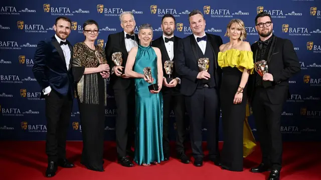 Cast of Blue Lights holds five statuettes as they smile to the cameras while posing on the red carpet