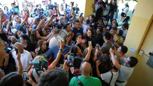 Wide shot of Sara Duterte among a crowd of supporters trying to take photos of her