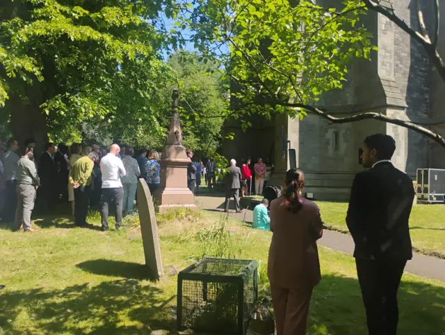 People stand solemnly in a church yard