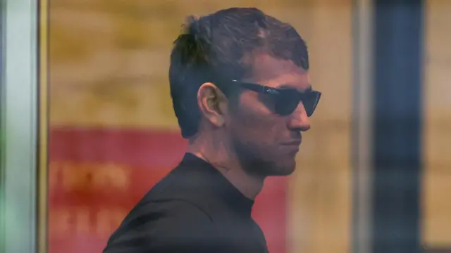 Alex Fine, husband of Casandra Ventura also known as Cassie, is wearing a black shirt and black sunglasses.
