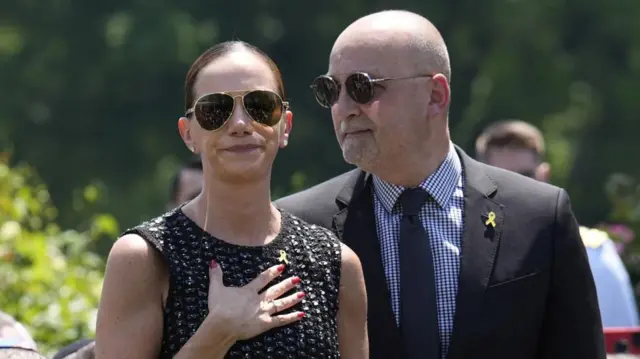 Yael and Adi Alexander, she has a hand over her heart and both are wearing yellow ribbon pins, a symbol of solidarity with hostages solidarity in Gaza