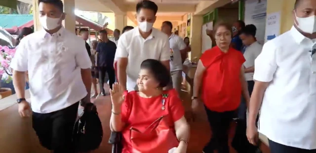 Imelda Marcos is wheeled into a polling station