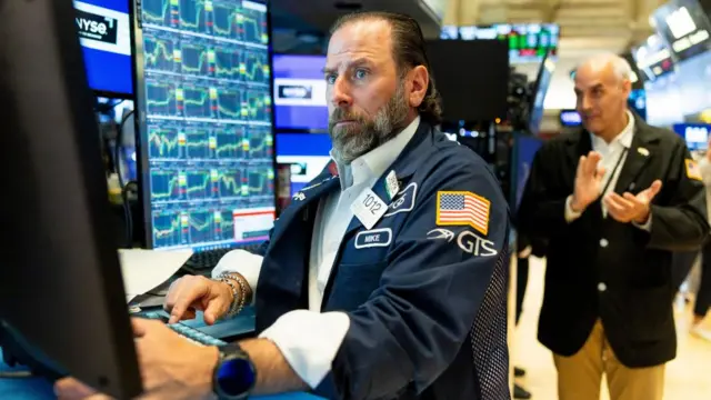 An NYSE trader is looking at screens showing stocks surging.