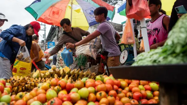 A female shopper puts fruit into her bag at a street market.