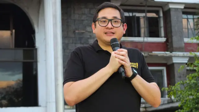 Bam Aquino, in black T-shirt, speaks while holding a mic