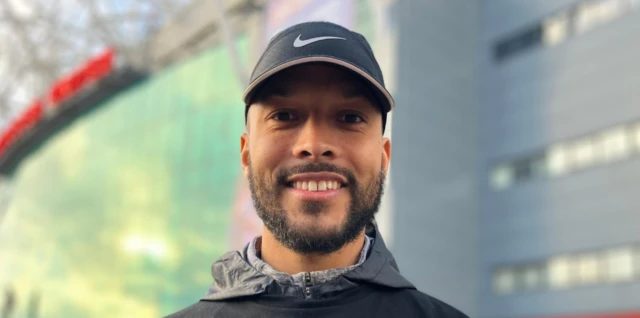 Joe Thompson, wearing a baseball cap, smiles outside Man Utd's Old Trafforrd groundd