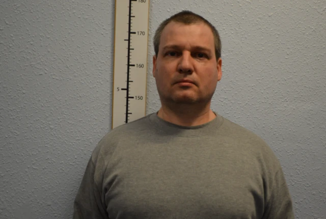 Orlin Roussev stood next to a measuring stick in a grey t shirt