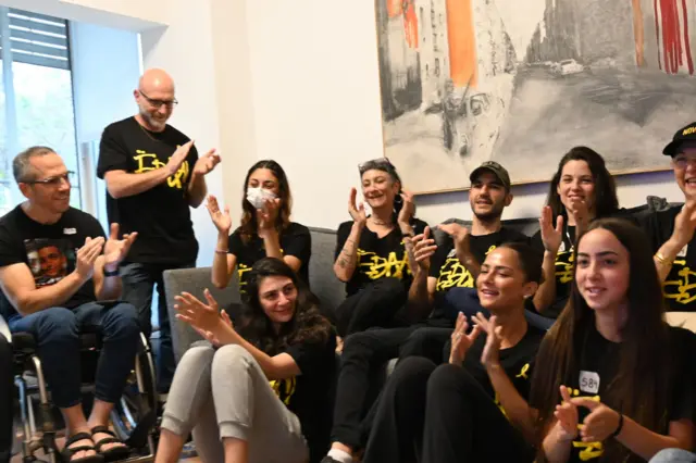 People sat on sofa clapping and smiling