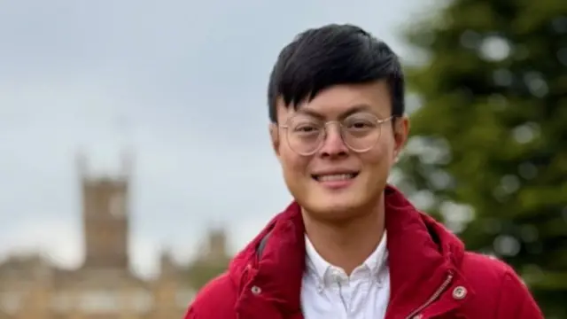 Headshot of Tsao wearing a red coat smiling at the camera outside