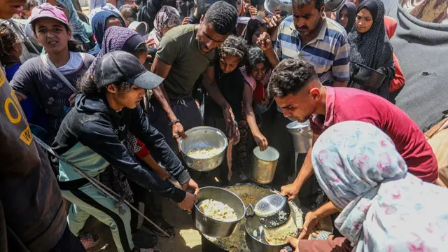 Palestinians receive hot meals distributed by charity organizations amid the ongoing Israeli attacks and total blockade,