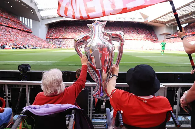 Liverpool fans at Anfield hold up inflatable Premier League trophy