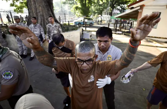 An inmate is checked before entering a polling station in the Philippines.
