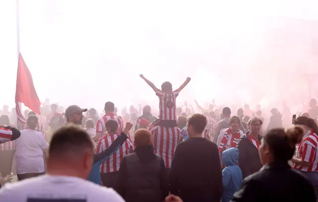 Sunderland fans enjoy the pre match atmosphere outside the stadium as red smoke from flares settles