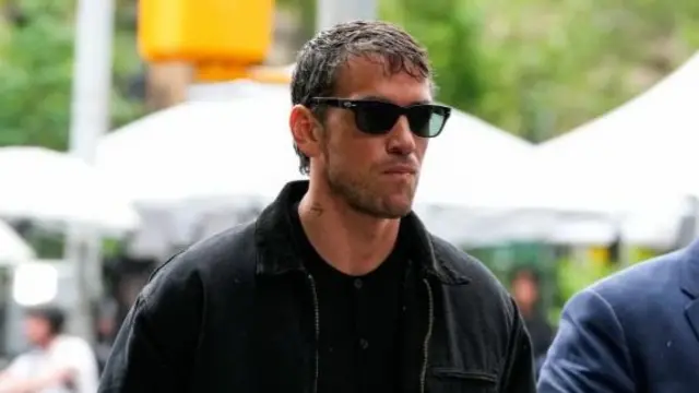 Man in black outfit and sunglasses walks