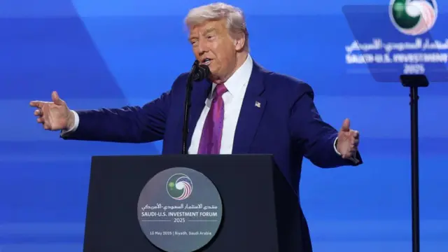 Donald Trump delivering a speech at a podium with his arms outstretched