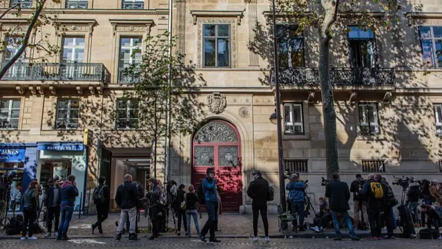 People standing on a street outside a building with a red double door
