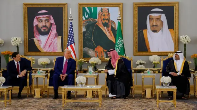 Marco Rubio, Donald Trump, MBS and another Saudi official sitting in chairs, behind them are three portraits and a US and Saudi flag