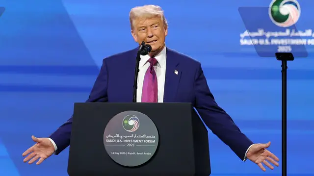 Trump holds his hands out as he speaks at a podium