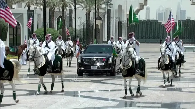 Horses with people carrying Saudi and US flags surround Trump's car as it arrives
