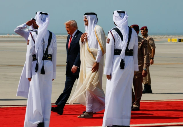 U.S. President Donald Trump walks with Qatar's Emir Tamim bin Hamad Al Thani upon his arrival at Hamad International Airport