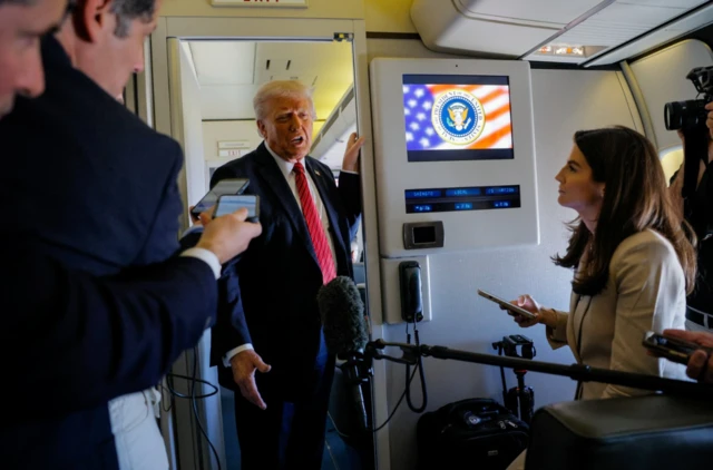 U.S. President Donald Trump speaks to the press on board Air Force One en route to Doha