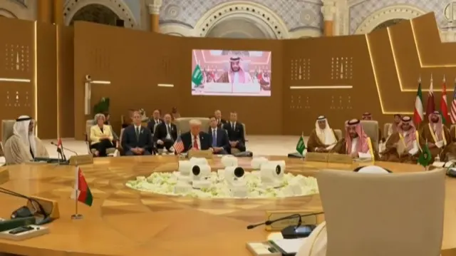 Trump siting at a large table with people sat behind him