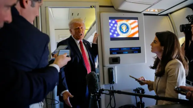 U.S. President Donald Trump speaks to the press on board Air Force One en route to Doha