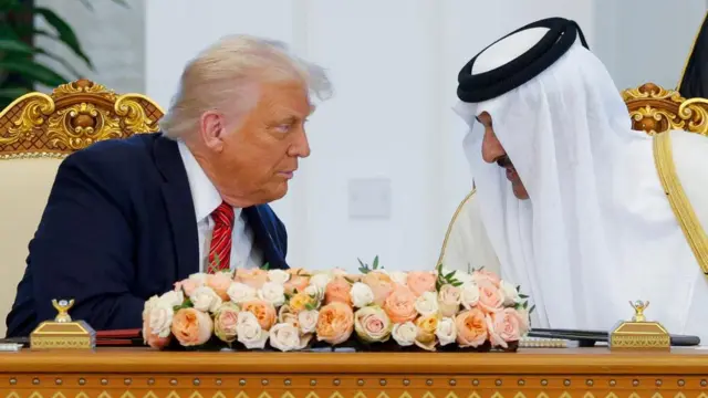 US President Donald Trump and Qatar's Emir Tamim bin Hamad Al Thani sitting behind a desk speaking to each other