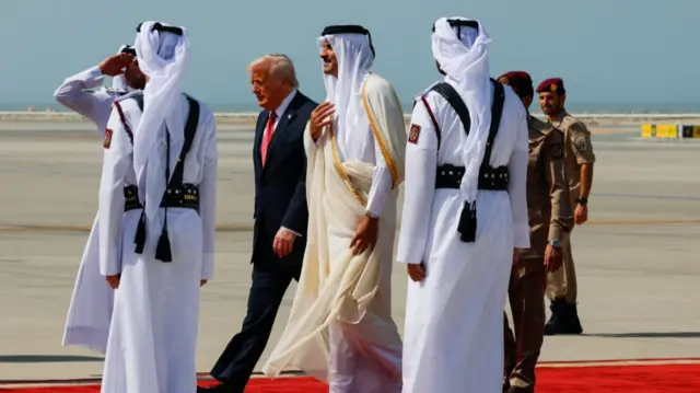 U.S. President Donald Trump walks with Qatar's Emir Tamim bin Hamad Al Thani upon his arrival at Hamad International Airport
