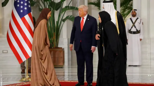 US president Donald Trump and the Qatari Emir speaking to a woman at the palace doors.
