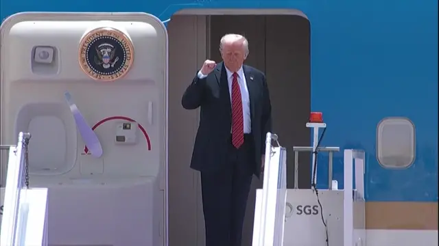 President Trump stands at the entrance to Air Force One with his fist punching the air.