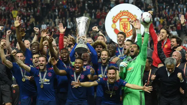 United players and staff lifting the trophy.