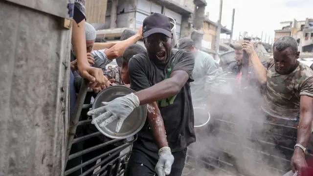 A man in black baseball cap and white silicone gloves at a food distribution centre in Gaza.
