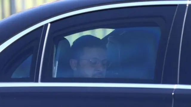 Ukrainian President Volodymyr Zelensky, wearing circular glasses, sits in a car on his way to meet his Turkish counterpart in Ankara