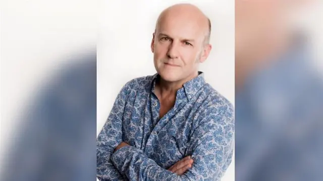 Professor Paul Howard-Jones pictured in a blue floral shirt with his arms folded.
