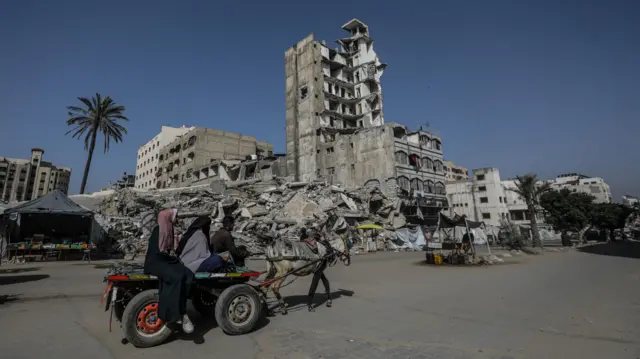 Displaced Palestinians move in the streets of Gaza City, near a destroyed building