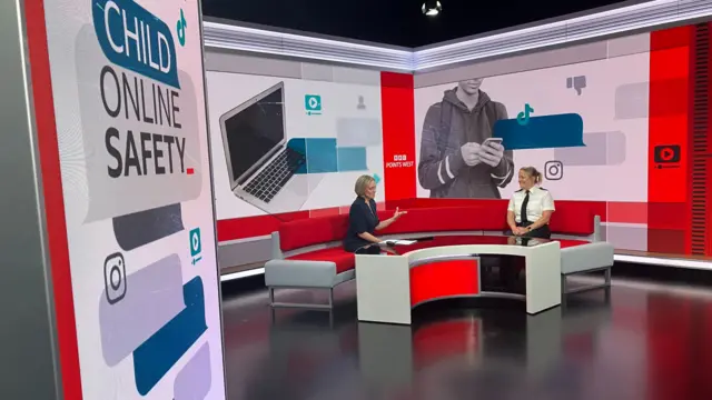 Two women speaking on a red sofa inside a large, digital TV set for news programmes