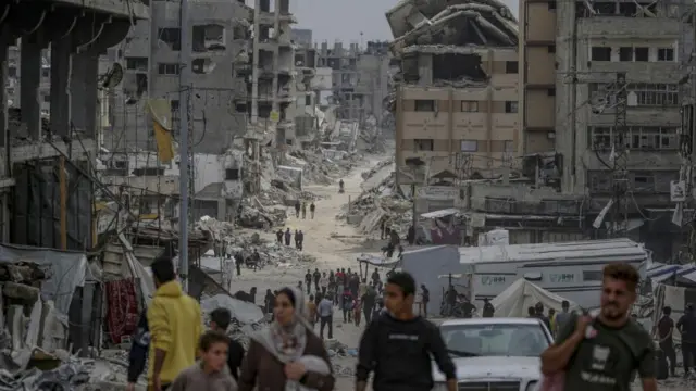 A view down a street in Gaza City, where people carry their belongings between destroyed buildings