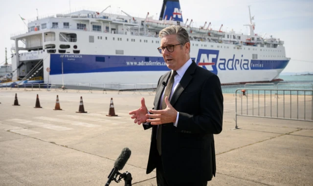 Britain's Prime Minister Keir Starmer is interviewed at a port in Albania next to a huge ship which has been docked in the port next to him