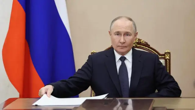 Putin chairing last night's meeting of the talks delegation, he is seated at a table with papers in front of him and a Russian flag behind him