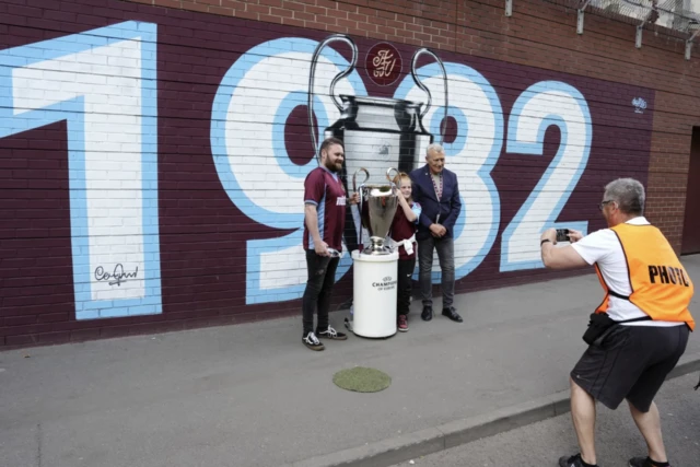Former Aston Villa player Tony Morley poses for photographs with fans by a mural outside the stadium