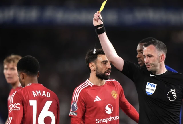 Referee Christopher Kavanagh shows a yellow card to Manchester United's Amad Diallo d
