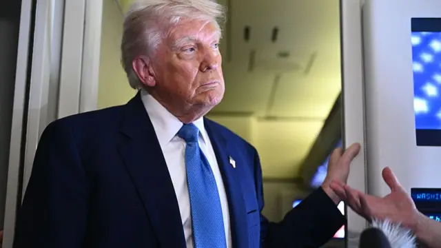 US President Donald Trump speaks to members of the media accompanying him aboard Airforce One