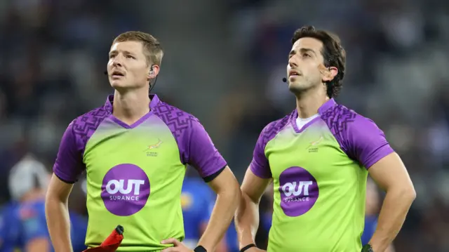 Assistant referee Hanru van Rooyen and referee Gianluca Gnecchi look at the big screen
