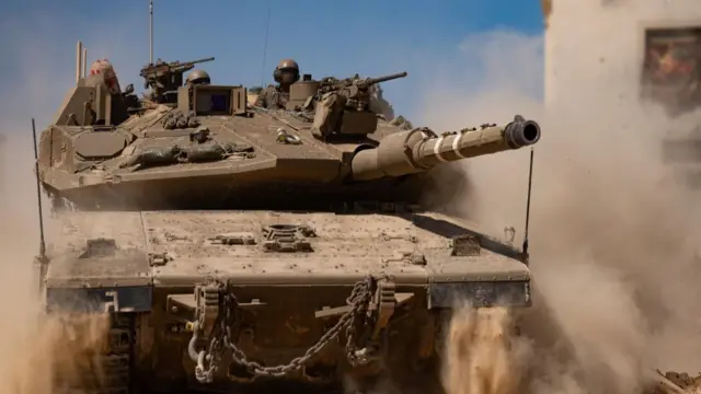 A tank moves through a dusty landscape
